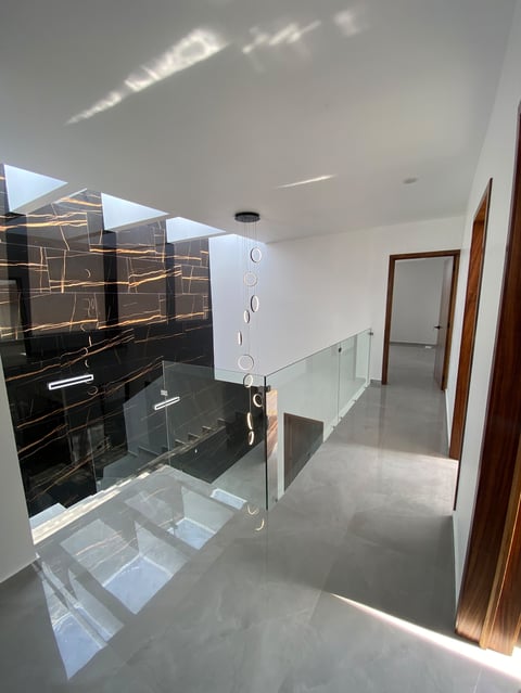 Modern kitchen showroom with sleek black cabinetry, glass railing, polished concrete flooring, and minimalist design under bright recessed lighting.