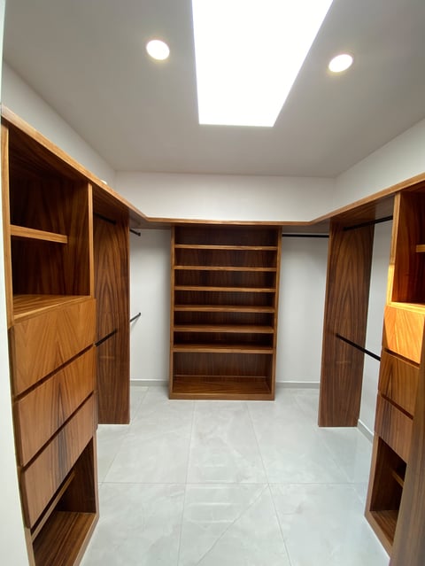 Modern walk-in closet with wooden cabinetry, shelving, recessed lighting, and white tile flooring